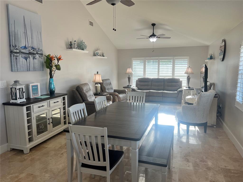 A living and dining area features a vaulted ceiling, tile floors, and neutral furniture — 6020 MIDNIGHT PASS ROAD UNIT 22, SARASOTA, FL