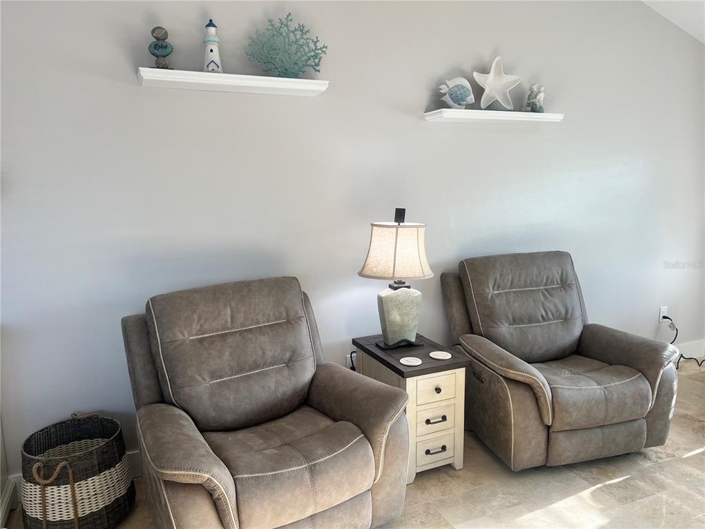 Two gray recliners sit on a tiled floor with a side table and wall shelves — 6020 MIDNIGHT PASS ROAD UNIT 22, SARASOTA, FL