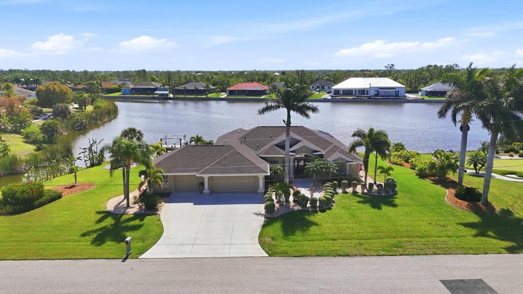 An aerial view of a single-story house with a driveway and lawn facing a canal — 13561 BLAKE DRIVE, PORT CHARLOTTE, FL