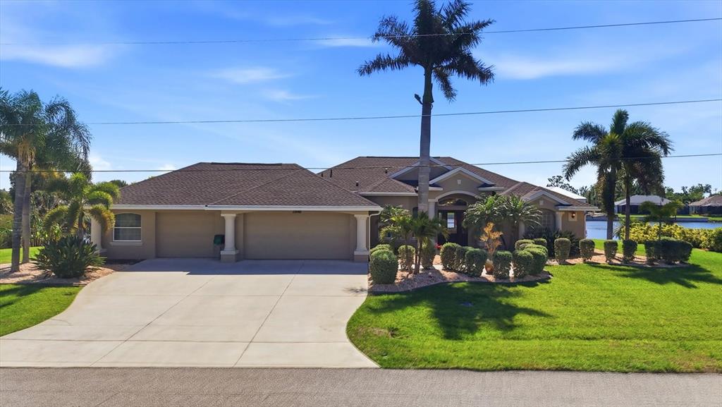 A single-story house with a three-car garage, palm trees, and a manicured lawn — 13561 BLAKE DRIVE, PORT CHARLOTTE, FL