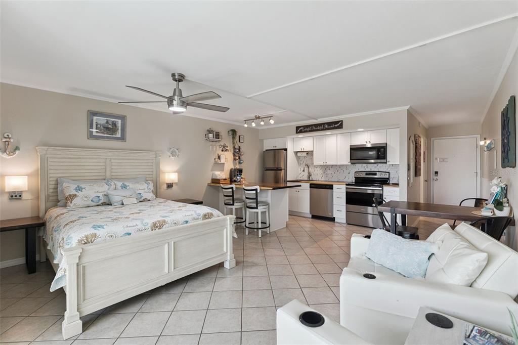 A studio apartment features a bed, a small kitchen with stainless appliances, and a seating area — 3700 S ATLANTIC AVENUE UNIT 309, NEW SMYRNA BEACH, FL