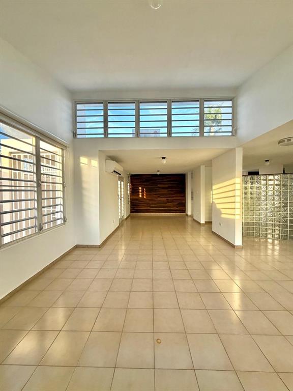 An open-plan living area features light-colored tile flooring, a wood-paneled accent wall, and clerestory windows — 2105 CALLE ANTIOQUIA, GUAYNABO, PR