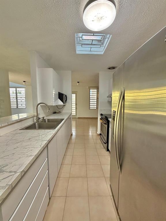 A kitchen features white cabinets, marble-look countertops, stainless steel appliances, and beige tile flooring — 2105 CALLE ANTIOQUIA, GUAYNABO, PR