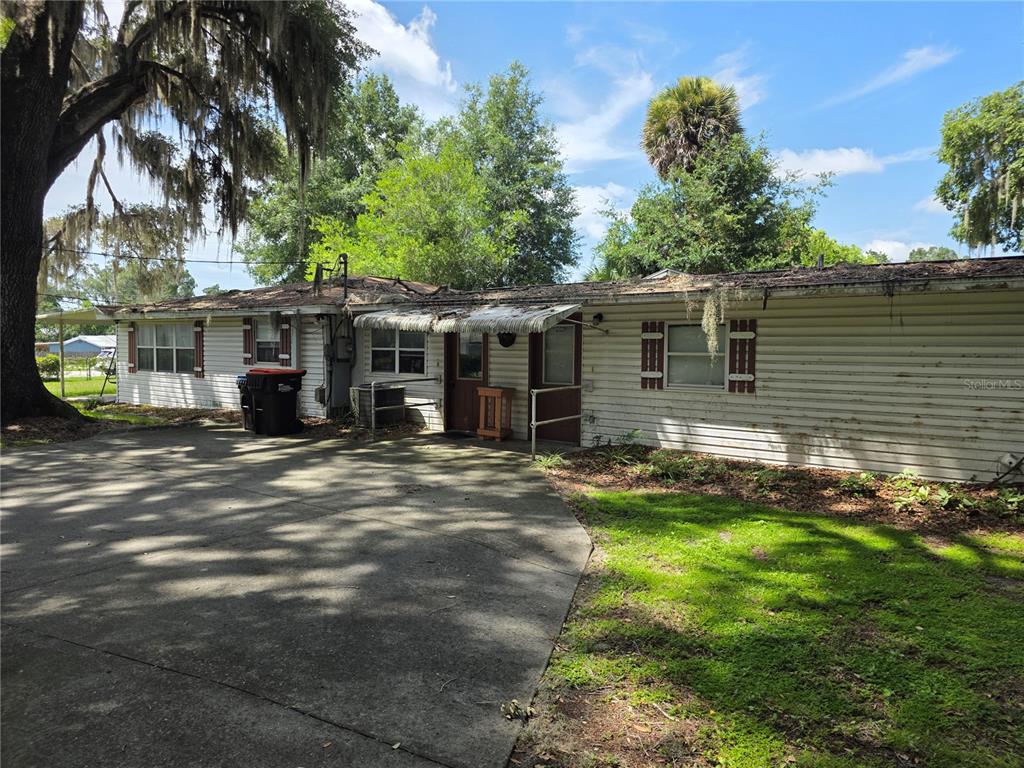 A single-story house with white siding, a concrete driveway, and a metal awning over doors — 6141 SE BABB ROAD, BELLEVIEW, FL