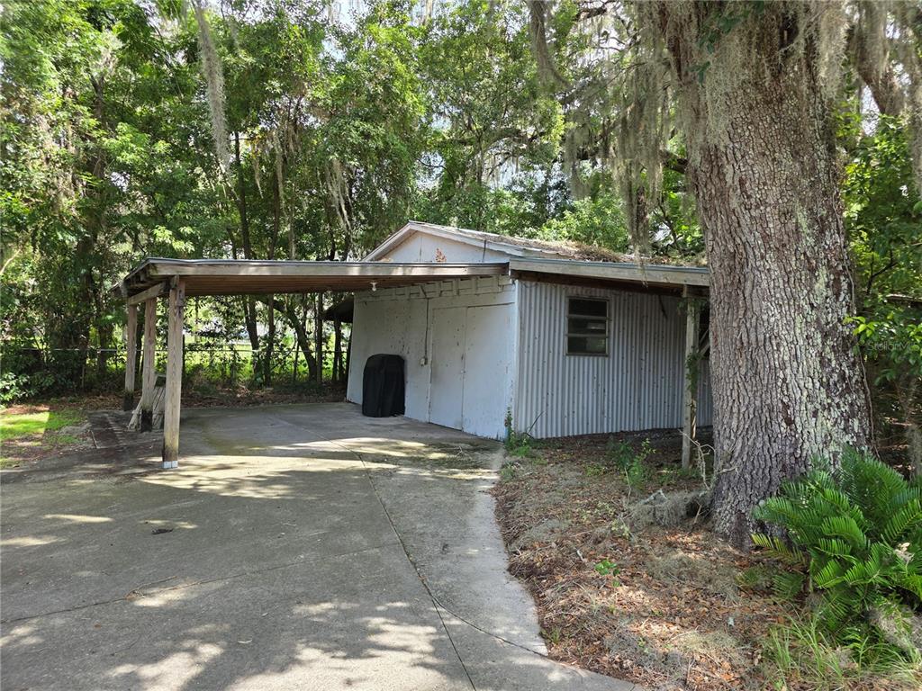 A detached white metal shed with a concrete driveway and an attached wooden carport — 6141 SE BABB ROAD, BELLEVIEW, FL