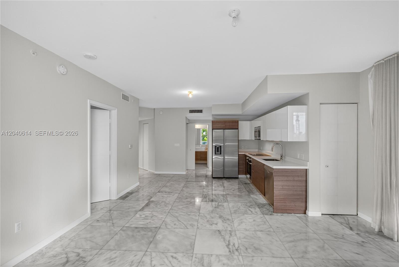 A kitchen with stainless steel appliances and wood-toned cabinets features marble-style tile flooring — 1010 SW 2nd Ave # 603, Miami FL 33130, MIAMI, FL