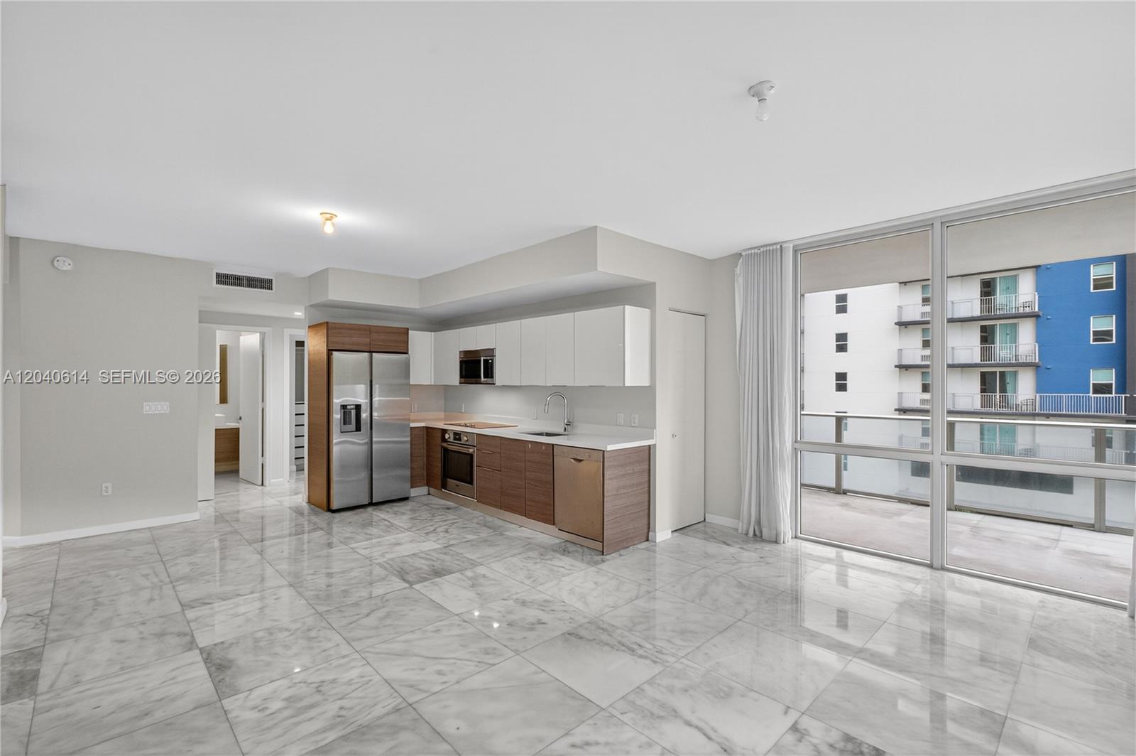 A modern kitchen features stainless steel appliances, wood-toned lower cabinets, and white upper cabinets — 1010 SW 2nd Ave # 603, Miami FL 33130, MIAMI, FL