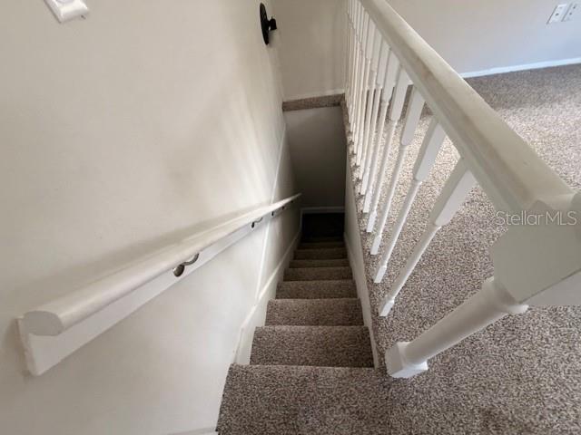 A carpeted staircase features a white wooden railing and a wall-mounted handrail — 3294 E WAGON TRAIL, HERNANDO, FL