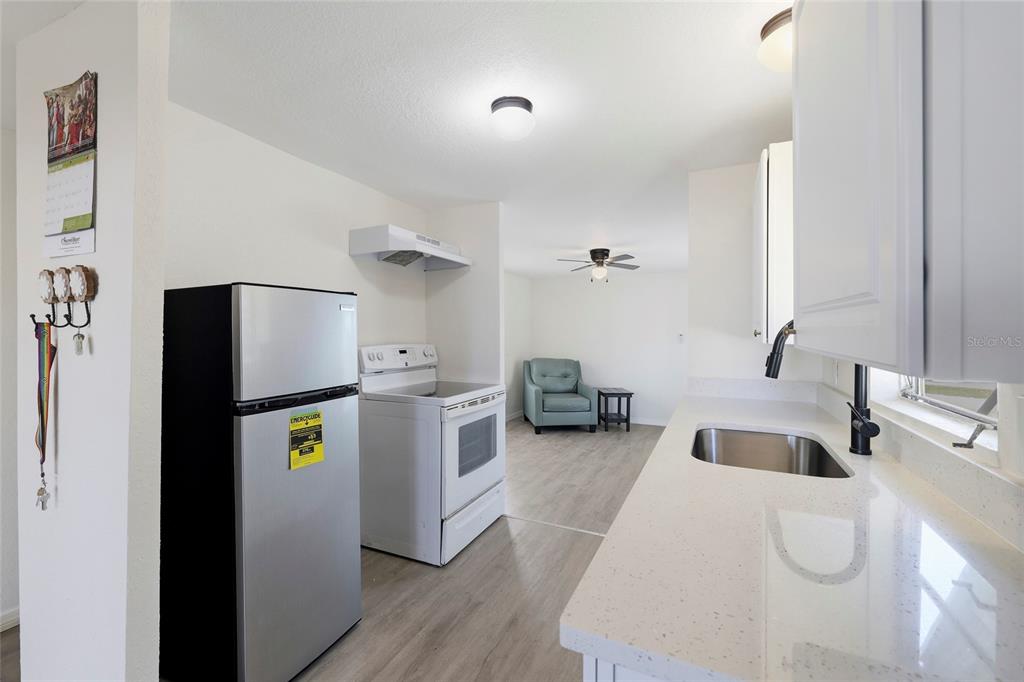 A kitchen with white cabinets and quartz countertops opens into a living area with flooring — 3300 COQUINA ESPLANADE, PUNTA GORDA, FL