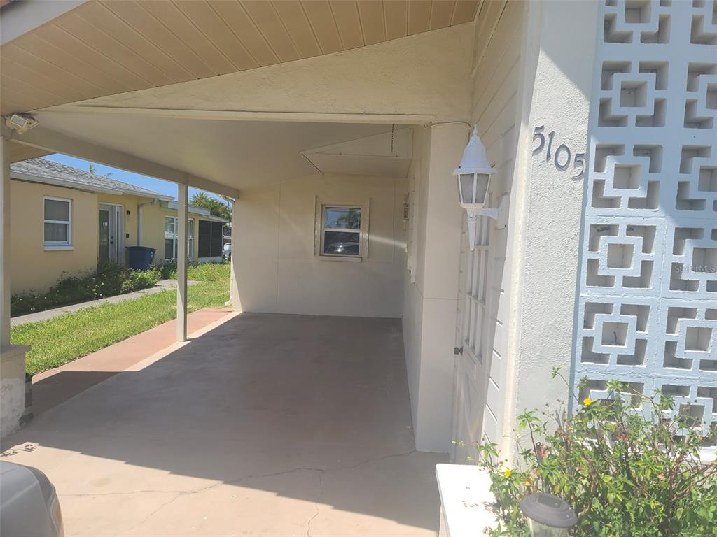 A covered carport area features a concrete floor, a white wall, and decorative block accents — 5105 BONITO DRIVE, NEW PORT RICHEY, FL
