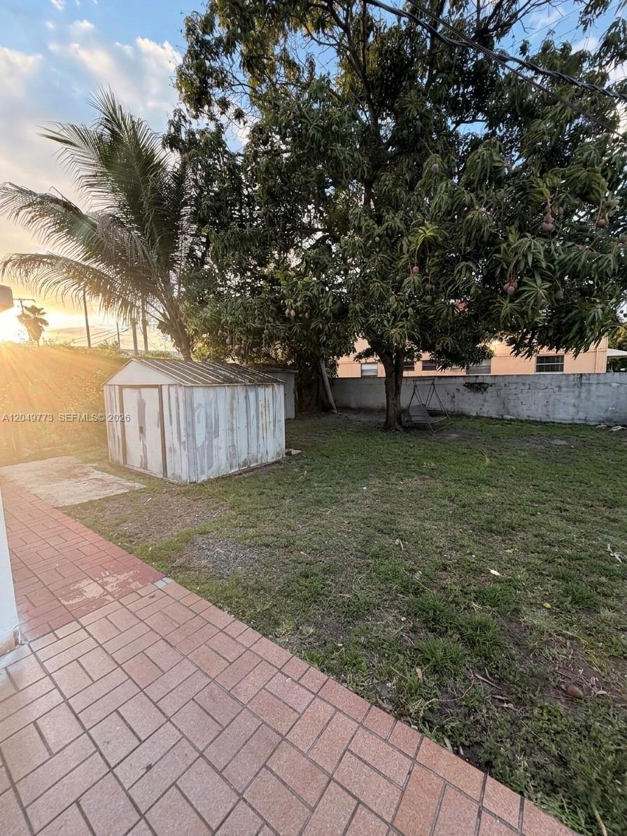 A backyard features a metal storage shed, a large mango tree, and a paved patio — 41 E 20th St, Hialeah FL 33010, HIALEAH, FL