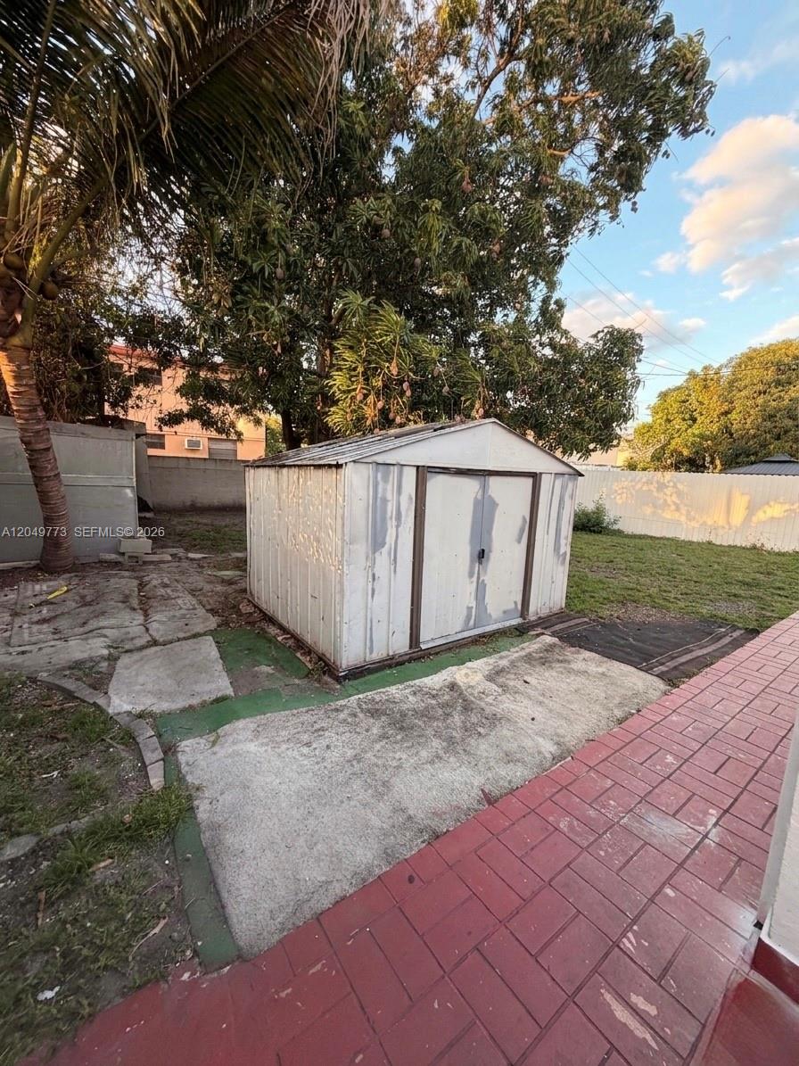 A metal storage shed sits on a concrete pad in a backyard with trees — 41 E 20th St, Hialeah FL 33010, HIALEAH, FL