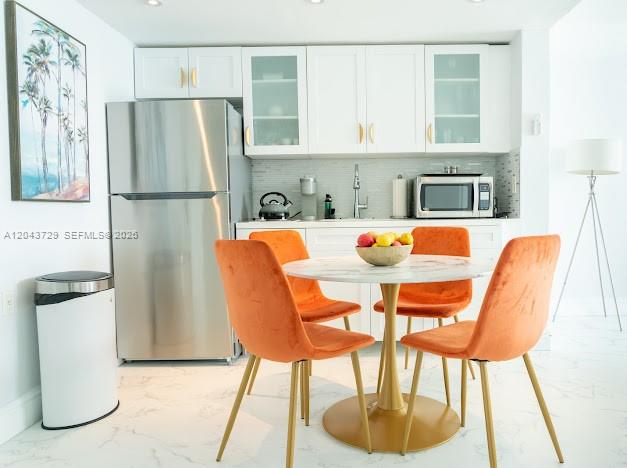 A kitchen with white cabinets, stainless steel appliances, and a round table with orange chairs — 1100 West Ave # 510, Miami Beach FL 33139, MIAMI BEACH, FL