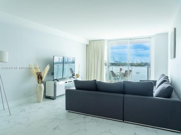 A living room with a grey sectional sofa, marble floors, and a balcony overlooking water — 1100 West Ave # 510, Miami Beach FL 33139, MIAMI BEACH, FL