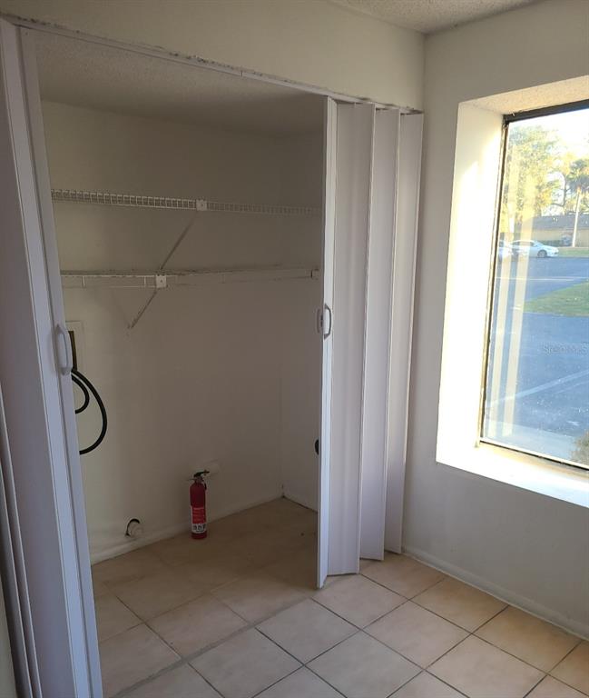 A closet with wire shelving and a fire extinguisher sits next to a large window — 4916 SILVER OAKS VLG UNIT E, ORLANDO, FL