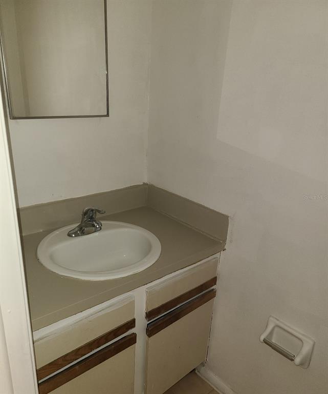 A bathroom vanity with a white sink, chrome faucet, and wood-trimmed cabinets — 4916 SILVER OAKS VLG UNIT E, ORLANDO, FL