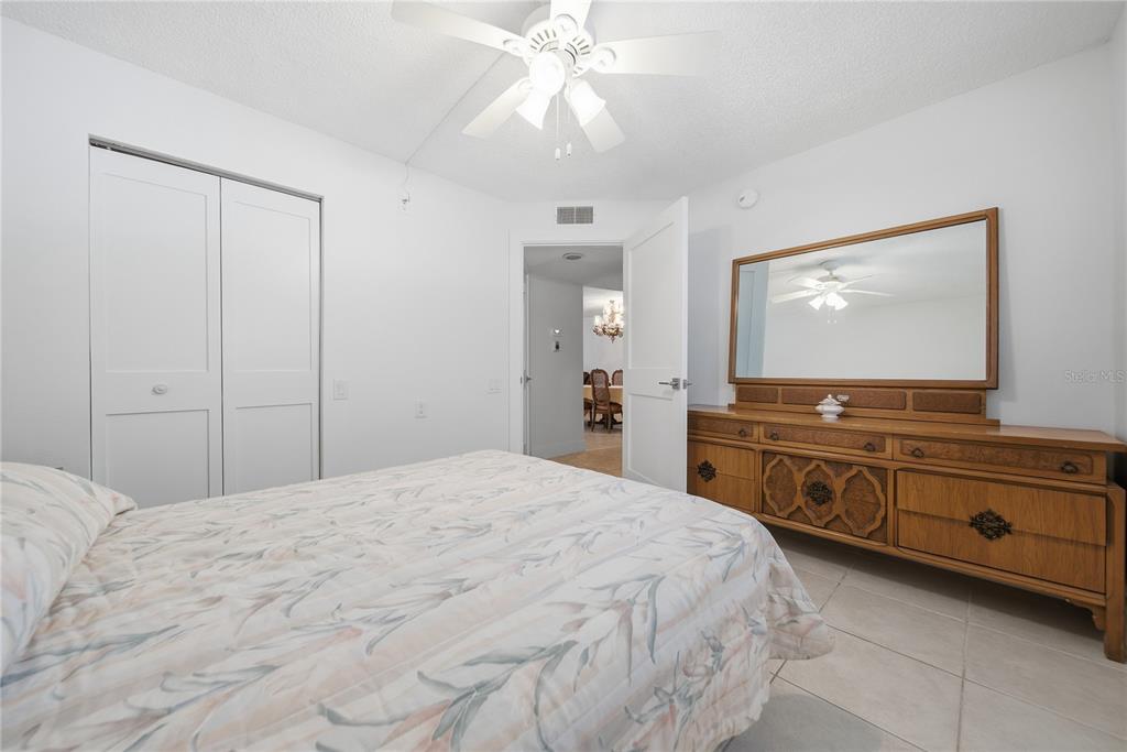 A bedroom features a bed, a wooden dresser with a mirror, and a ceiling fan — 1247 S MARTIN LUTHER KING JR AVENUE UNIT 107, CLEARWATER, FL