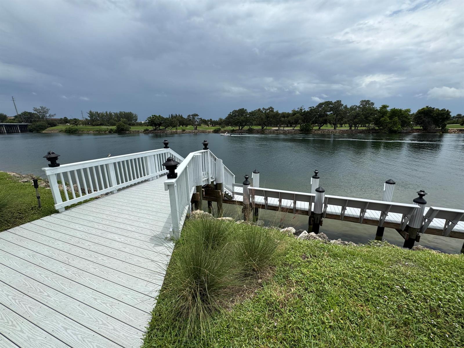 A white wooden dock extends over a calm river toward a tree-lined shore — 336 Golfview Road # 706, North Palm Beach FL 33408, NORTH PALM BEACH, FL