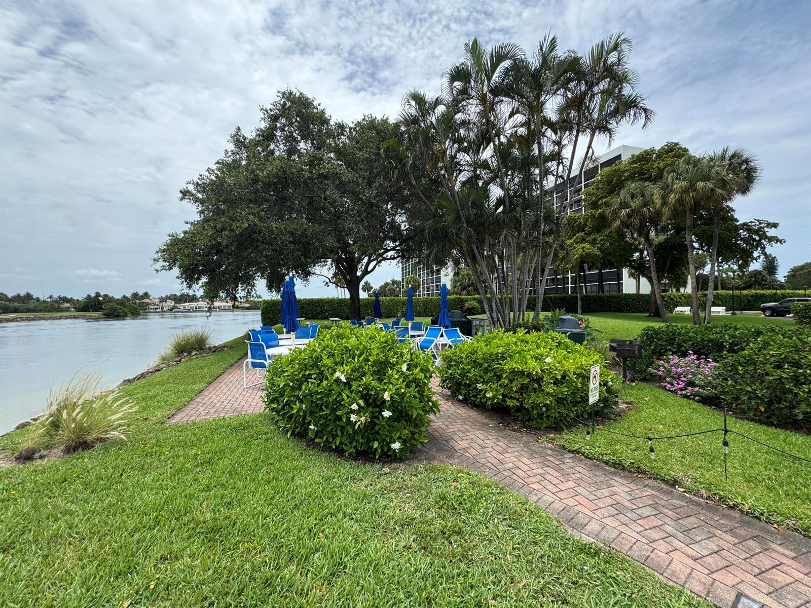 A brick patio with outdoor seating overlooks a waterway near palm trees and a building — 336 Golfview Road # 706, North Palm Beach FL 33408, NORTH PALM BEACH, FL