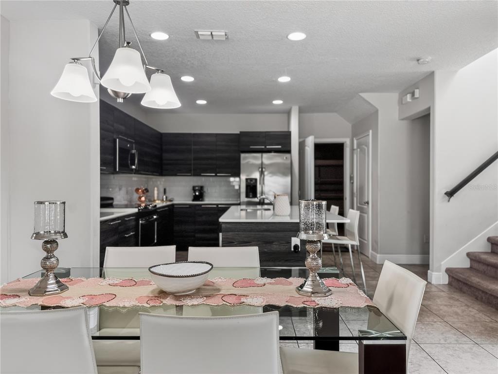 A dining area with a glass table overlooks a modern kitchen with dark wood cabinets — 127 KENNY BOULEVARD, HAINES CITY, FL