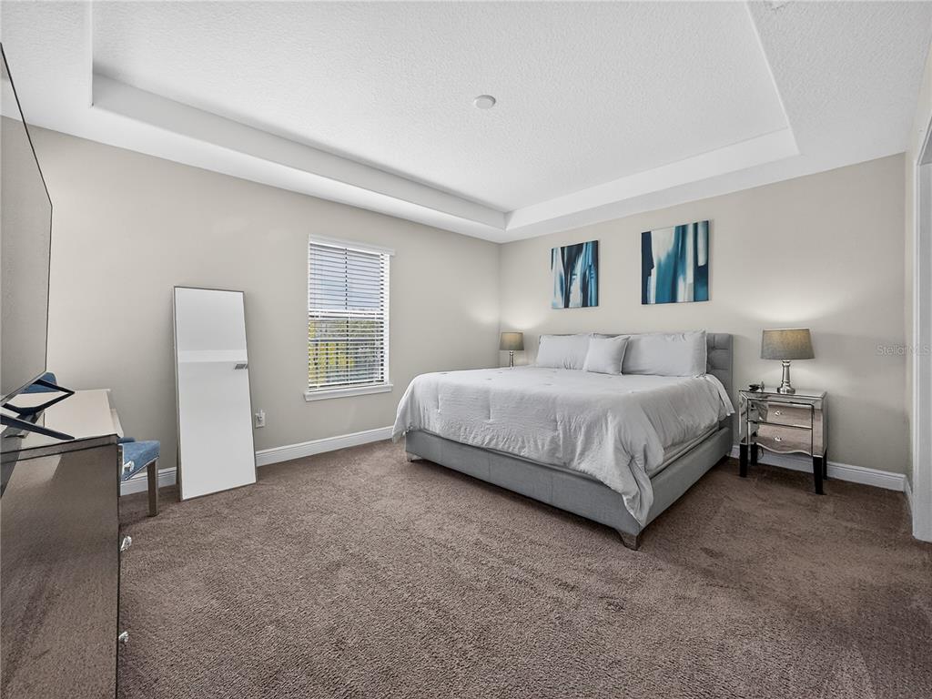 A bedroom features a king-sized bed, a mirrored nightstand, and a tall floor mirror — 127 KENNY BOULEVARD, HAINES CITY, FL