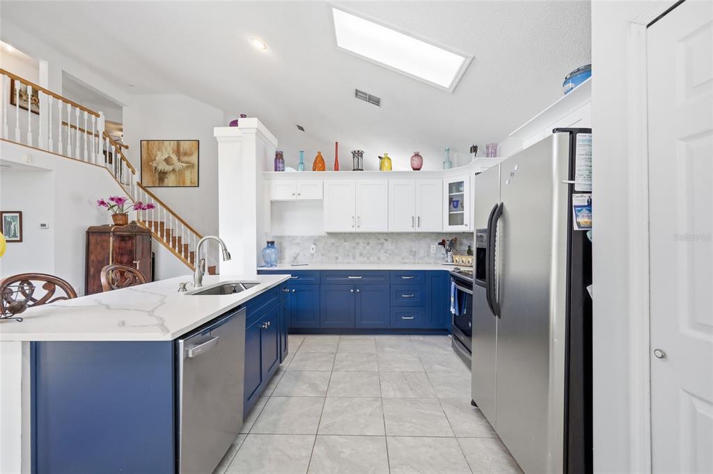 A kitchen features blue lower cabinets, white upper cabinets, a white island, and tile flooring — 13200 MALLARD COVE BOULEVARD, ORLANDO, FL