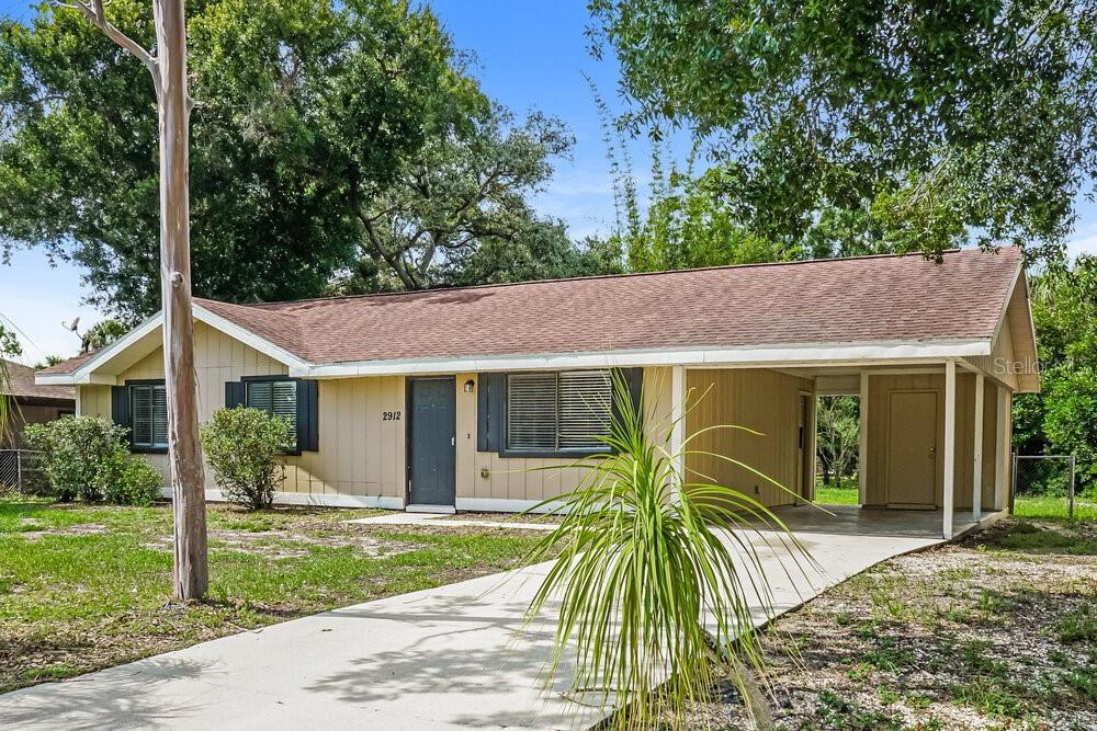 A single-story house with tan siding, a dark roof, and an attached carport — 2912 CRANE AVENUE, NORTH PORT, FL
