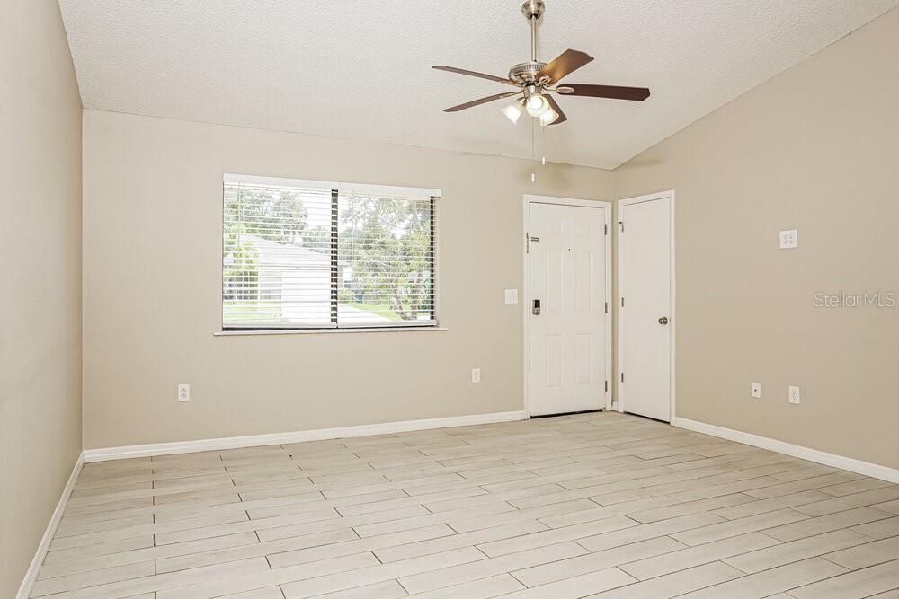 An empty room with light-colored tile flooring, a ceiling fan, and a window with blinds — 2912 CRANE AVENUE, NORTH PORT, FL