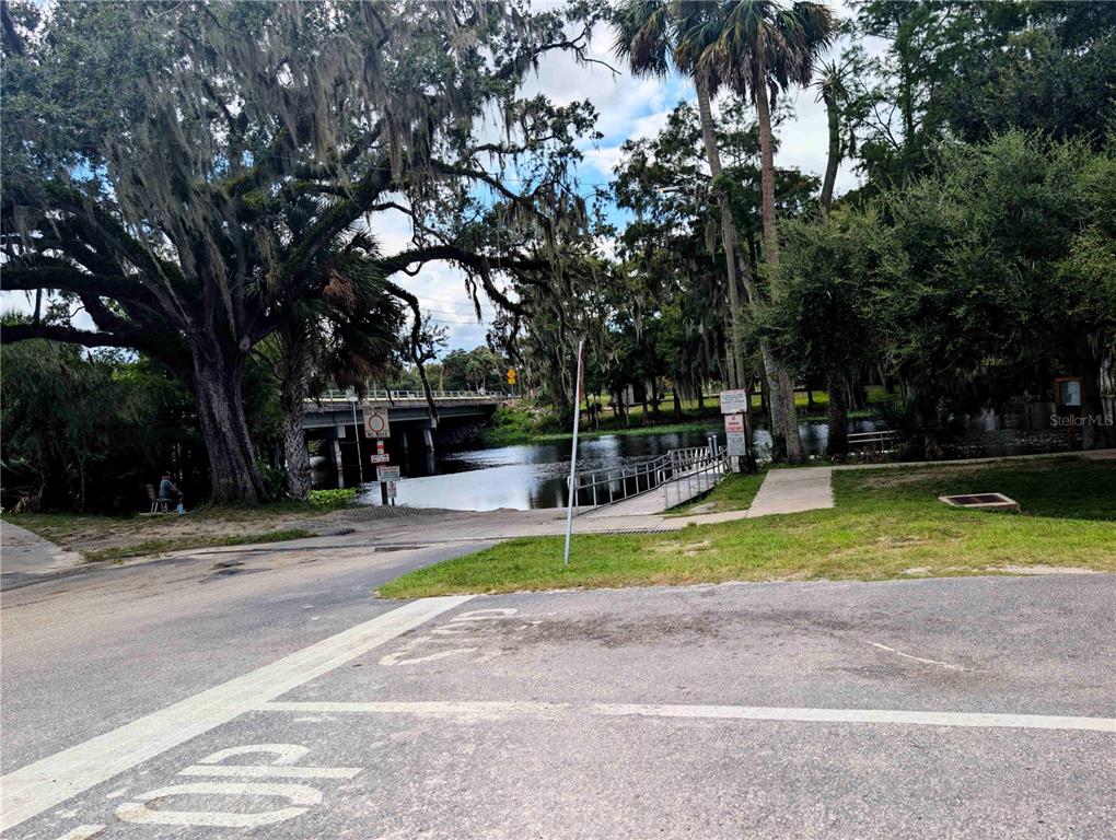 A paved boat ramp leads into a river beneath a bridge surrounded by large trees — 2259 W WILDFLOWER COURT, DUNNELLON, FL