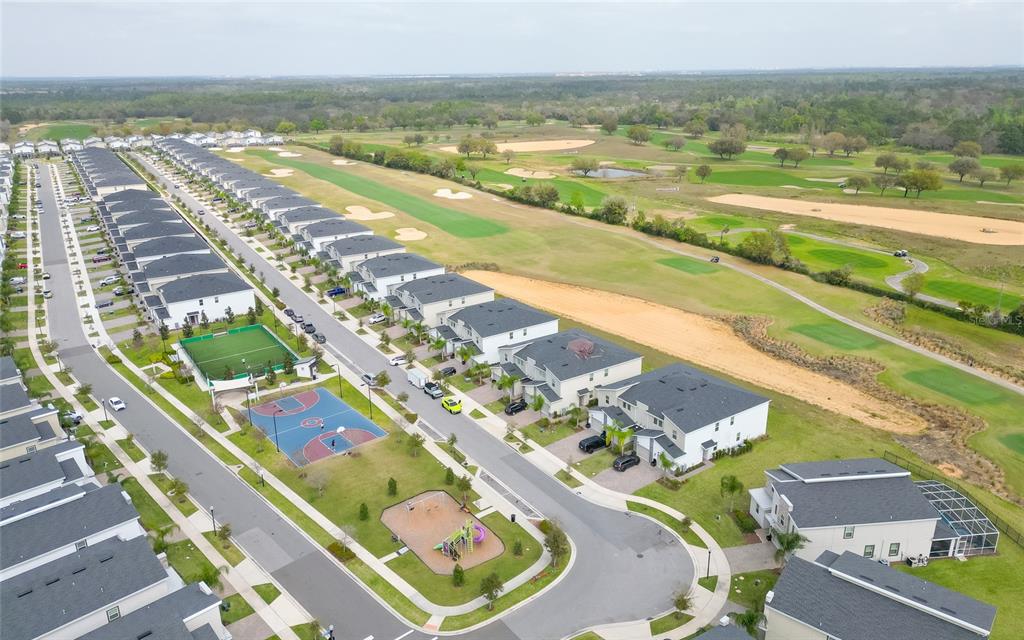 An aerial view shows a suburban neighborhood with townhouses, a playground, and a basketball court — 815 OCEAN COURSE AVENUE UNIT 815, DAVENPORT, FL