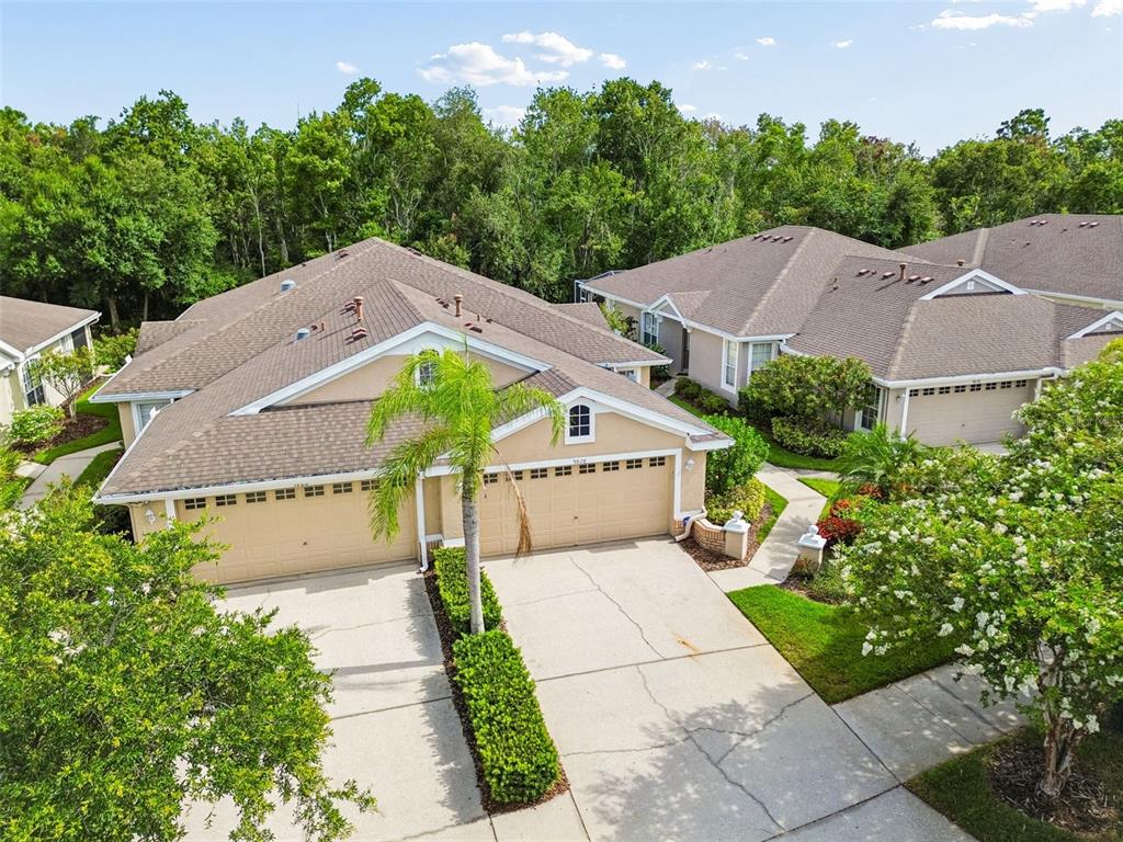 An aerial view shows two tan duplex homes with attached garages and surrounding landscaping — 9828 BRIDGETON DRIVE, TAMPA, FL