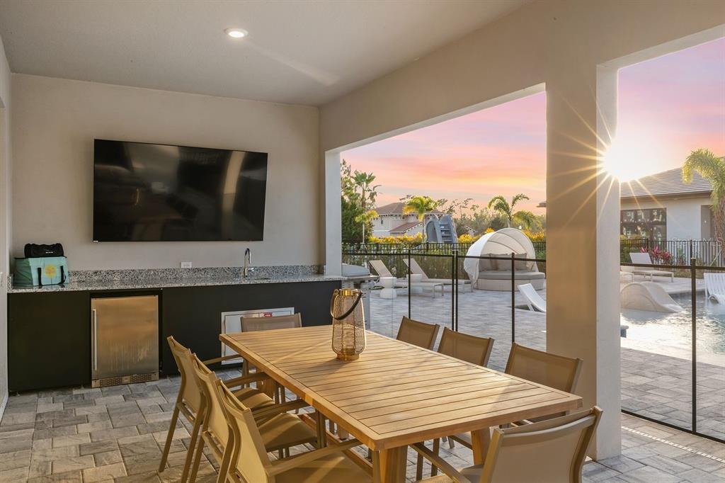 A covered outdoor patio features a dining table, a wet bar, and a swimming pool — 1008 COYOTE CREEK WAY, REUNION, FL