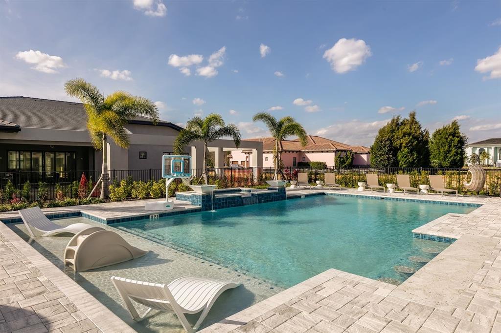 A swimming pool with a tanning ledge and basketball hoop sits behind a modern house — 1008 COYOTE CREEK WAY, REUNION, FL