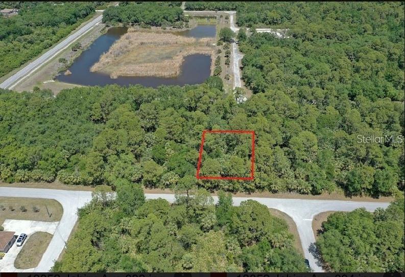 An aerial view shows a rectangular plot of land outlined in red amidst dense trees — 18052 JABIRU AVENUE, PORT CHARLOTTE, FL