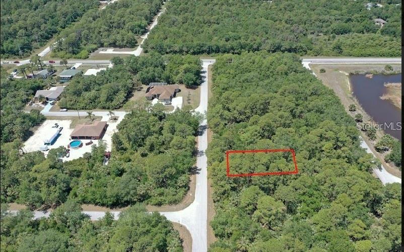 This aerial map shows a wooded lot outlined in red next to a paved road — 18052 JABIRU AVENUE, PORT CHARLOTTE, FL
