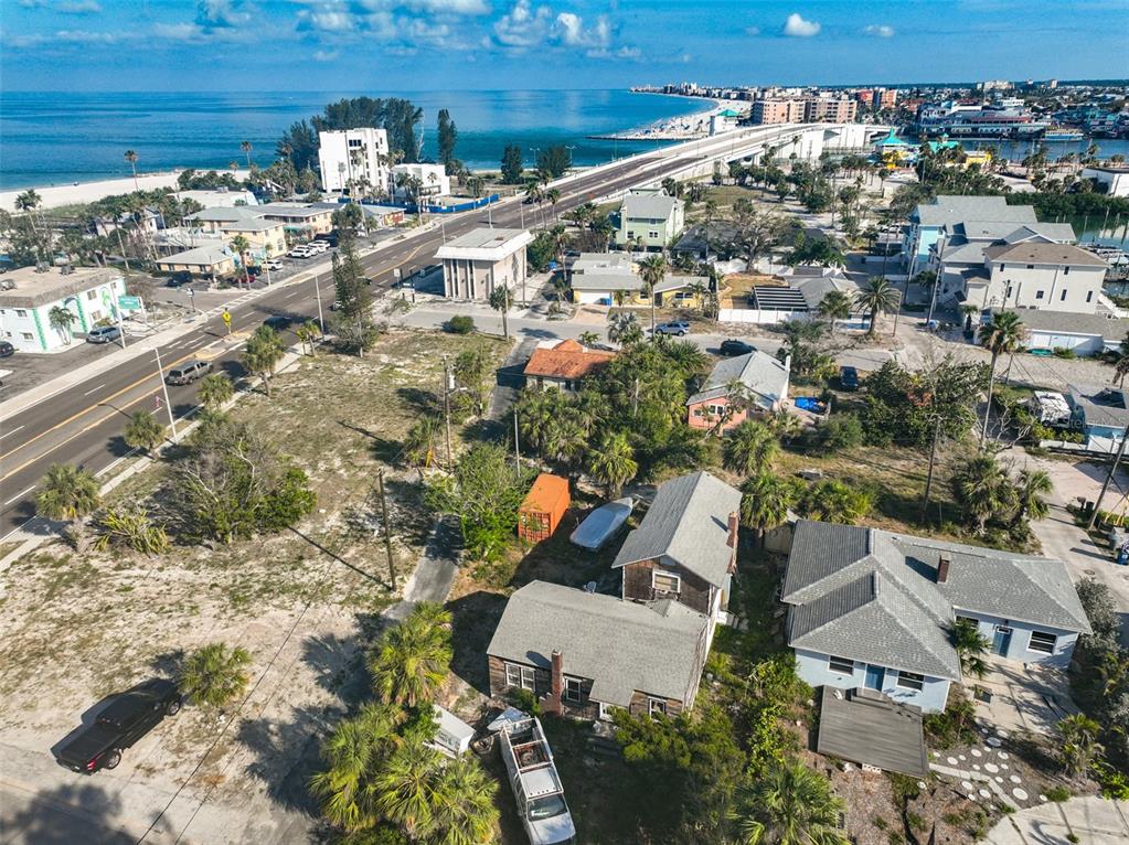 An aerial view shows houses, a road, and a bridge leading to a coastal beach area — 108 125TH AVENUE, TREASURE ISLAND, FL