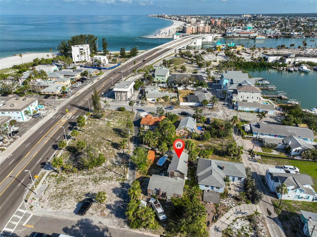 An aerial view shows a coastal neighborhood with a house marked by a red pin — 108 125TH AVENUE, TREASURE ISLAND, FL