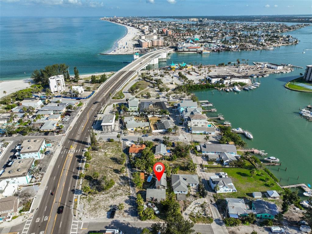 An aerial view shows a coastal neighborhood with a red location pin on a house — 108 125TH AVENUE, TREASURE ISLAND, FL