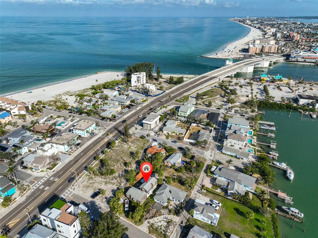 An aerial view shows a coastal neighborhood with a house marked by a red pin — 108 125TH AVENUE, TREASURE ISLAND, FL