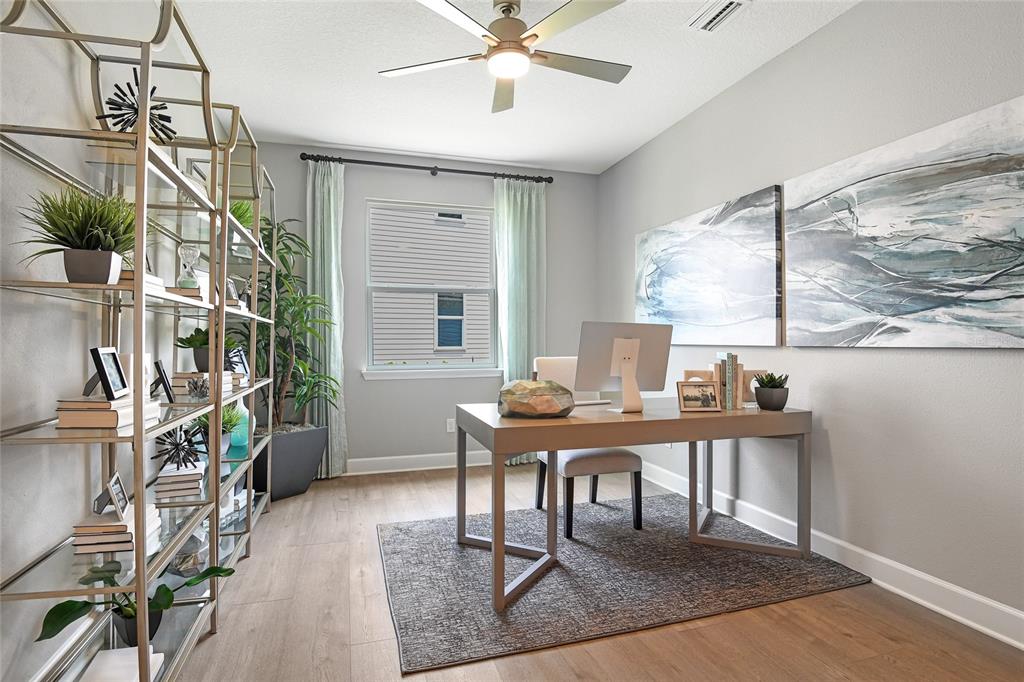 A home office features a desk, a tall metal shelving unit, and two large wall paintings — 65 PONCE PRESERVE DRIVE, PALM COAST, FL