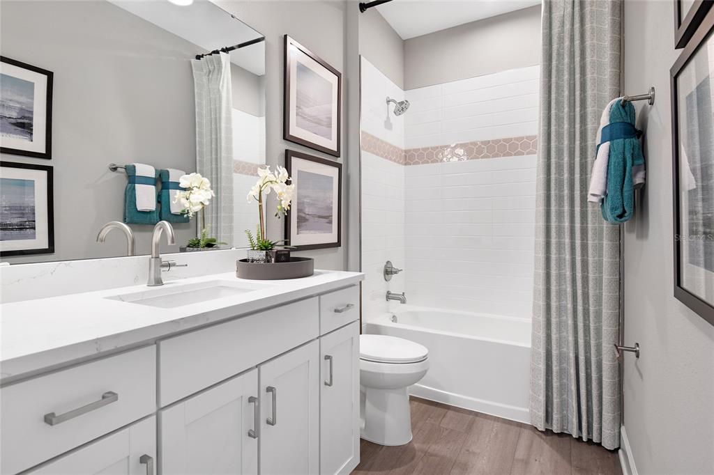 A modern bathroom features a white vanity, a tub-shower combination, and wood-look flooring — 65 PONCE PRESERVE DRIVE, PALM COAST, FL