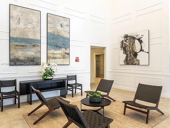 A modern lobby features white paneled walls, abstract artwork, and dark wooden furniture on a rug — 1091 Galiano St, Coral Gables FL 33134, CORAL GABLES, FL