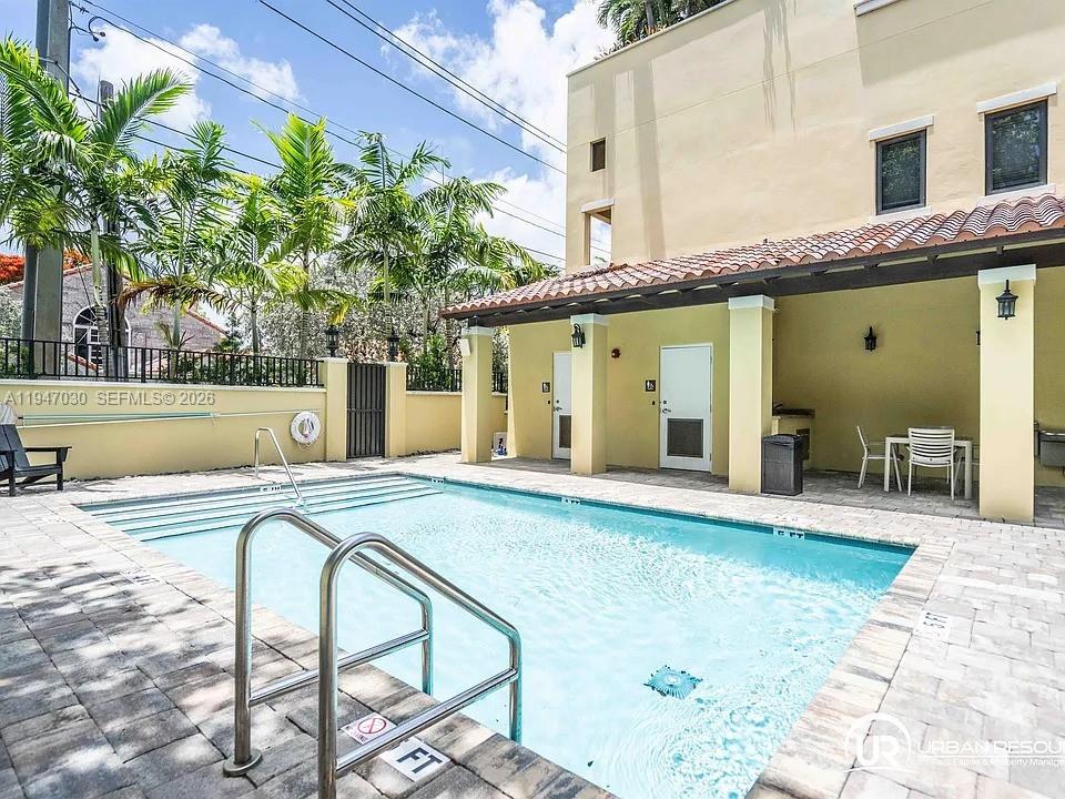 A swimming pool with a metal ladder sits in front of a tan building — 1091 Galiano St, Coral Gables FL 33134, CORAL GABLES, FL