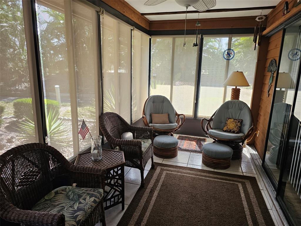 A sunroom features wicker furniture, tile flooring, area rugs, and large screened windows — 4139 66TH STREET CIRCLE W, BRADENTON, FL