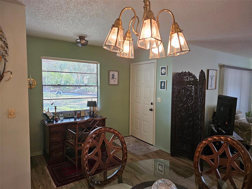A dining area features a glass table, wooden chairs, a desk, and a chandelier — 4139 66TH STREET CIRCLE W, BRADENTON, FL
