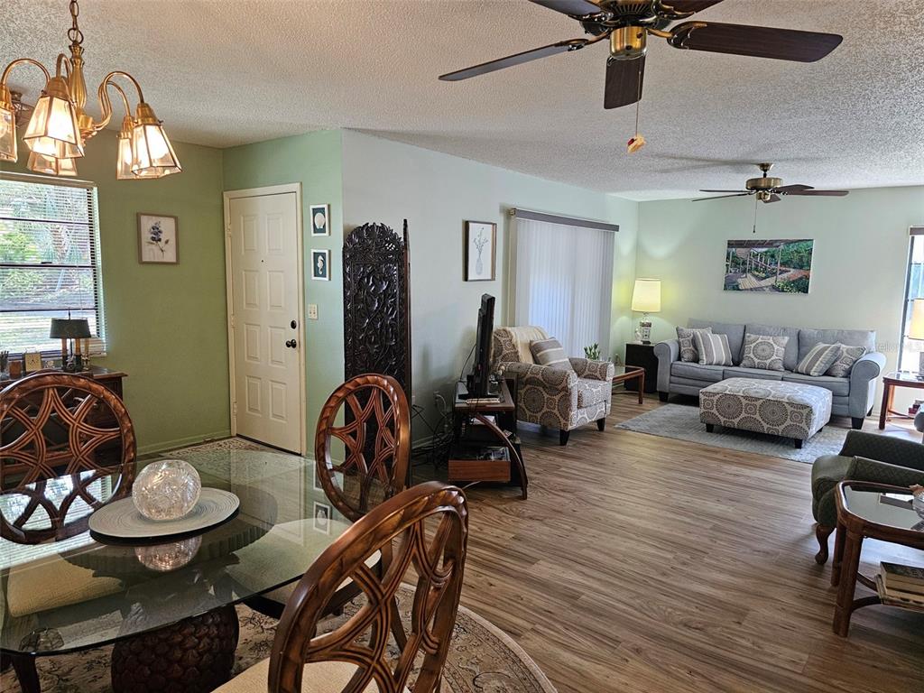 An open-concept living and dining area features light green walls, wood-look flooring, and ceiling fans — 4139 66TH STREET CIRCLE W, BRADENTON, FL