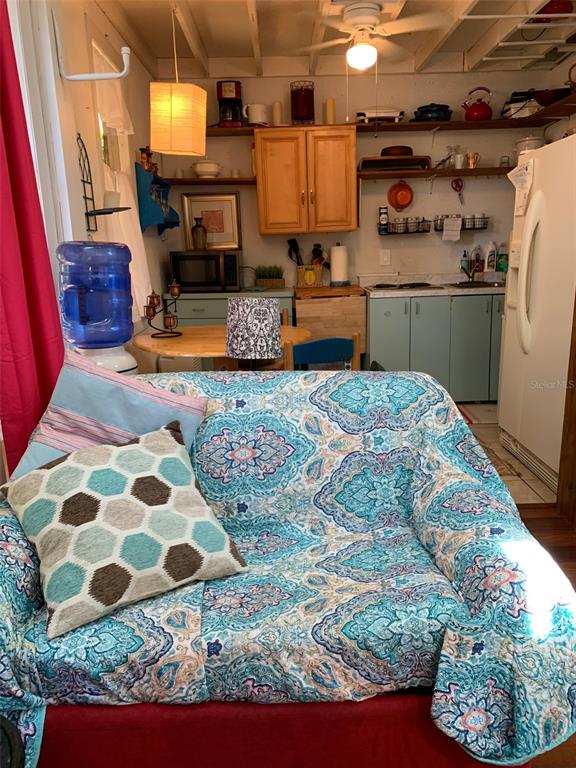 A living area with a patterned sofa faces a kitchen with wooden cabinets and appliances — 1653 BRAVO DRIVE, CLEARWATER, FL