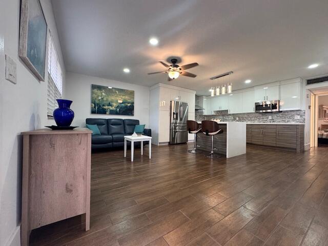 An open-concept kitchen and living area features wood-look tile flooring and a blue sofa — 187 Seville Terrace, Delray Beach FL 33446, DELRAY BEACH, FL