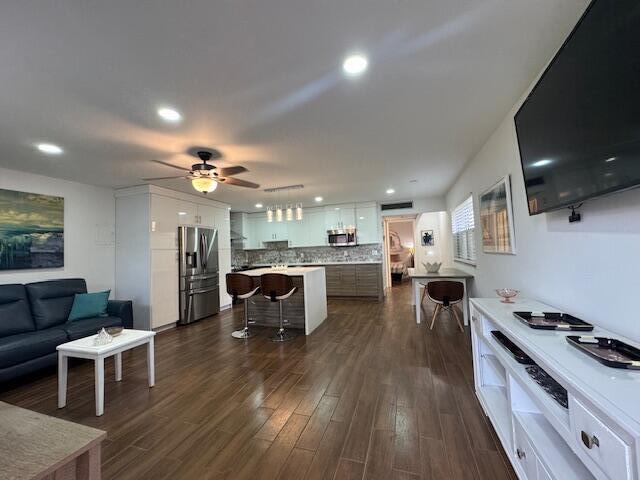 An open-concept living room and kitchen feature wood-look tile flooring and white cabinetry — 187 Seville Terrace, Delray Beach FL 33446, DELRAY BEACH, FL