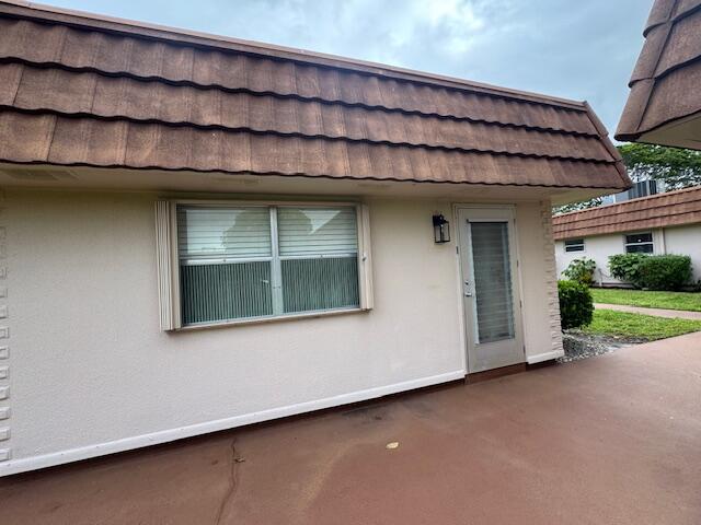 The exterior of a single-story building features a brown mansard roof and a white facade — 187 Seville Terrace, Delray Beach FL 33446, DELRAY BEACH, FL
